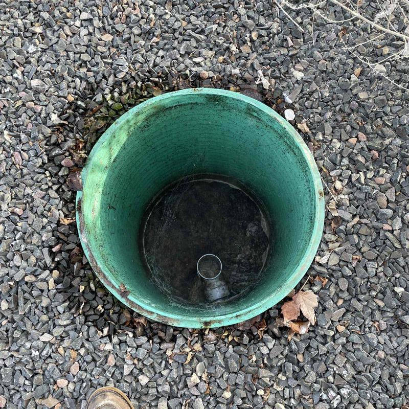 Septic tank access opening surrounded by gravel outdoors