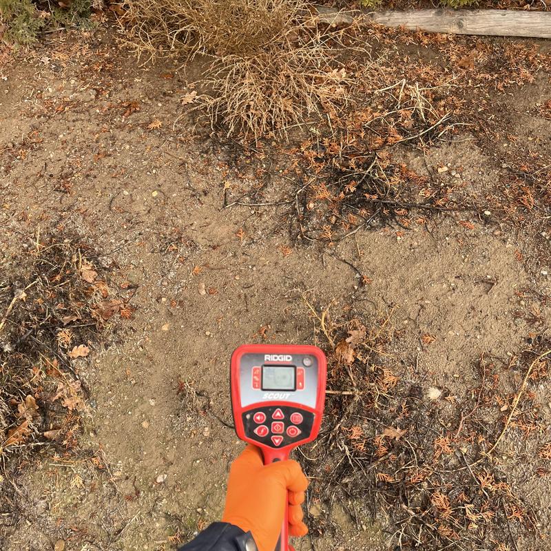 DWV pipe locator in soil with dry vegetation nearby