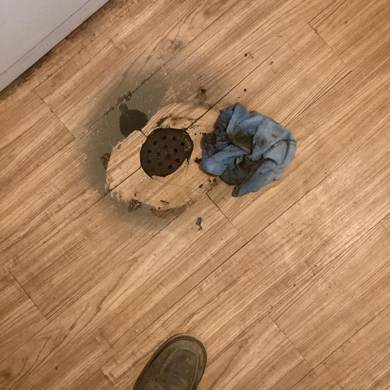 Basement floor drain with cast iron cap and debris