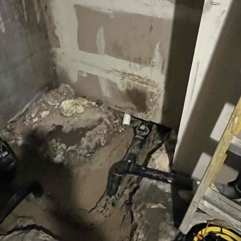 Basement sewer pipe with grease blockage and damaged floor
