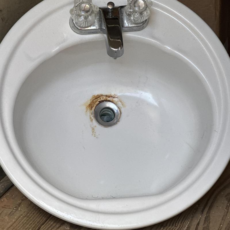 Bathroom sink with rust around drain and faucet