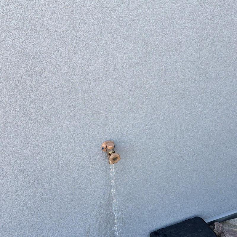 Hose bibb mounted on exterior stucco wall running water Hose bibb mounted on exterior stucco wall running water