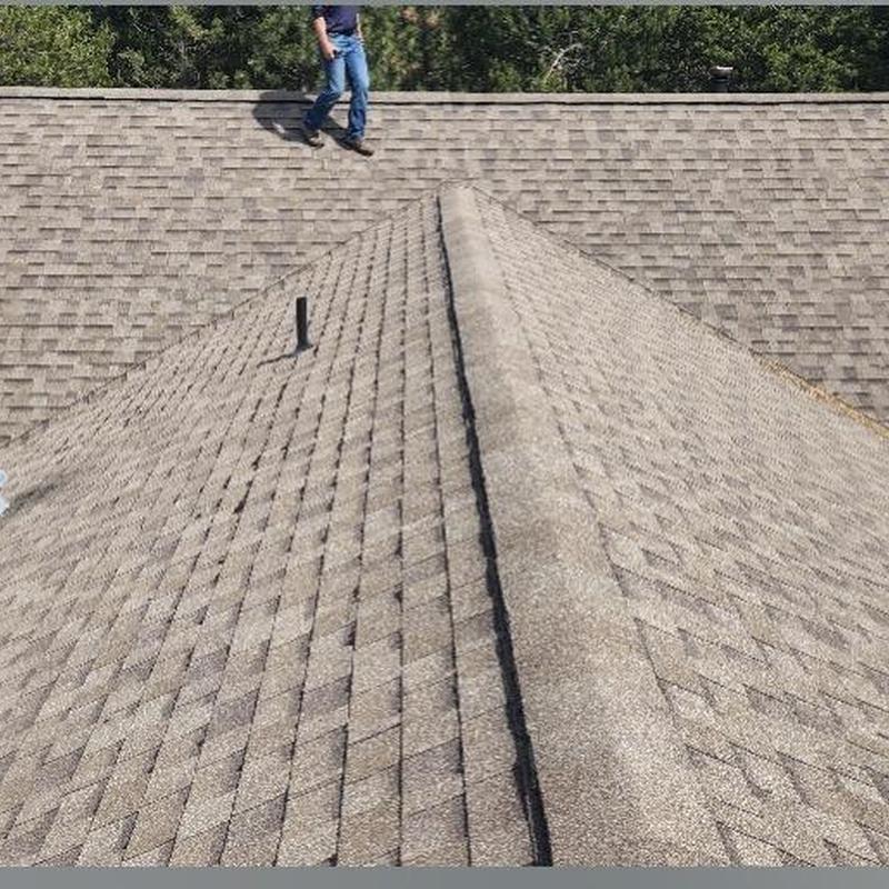 Asphalt shingle roof valleys and ridge with worker nearby