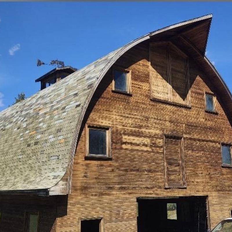 Curved shingle roof on wooden barn with repairs needed Curved shingle roof on wooden barn with repairs needed