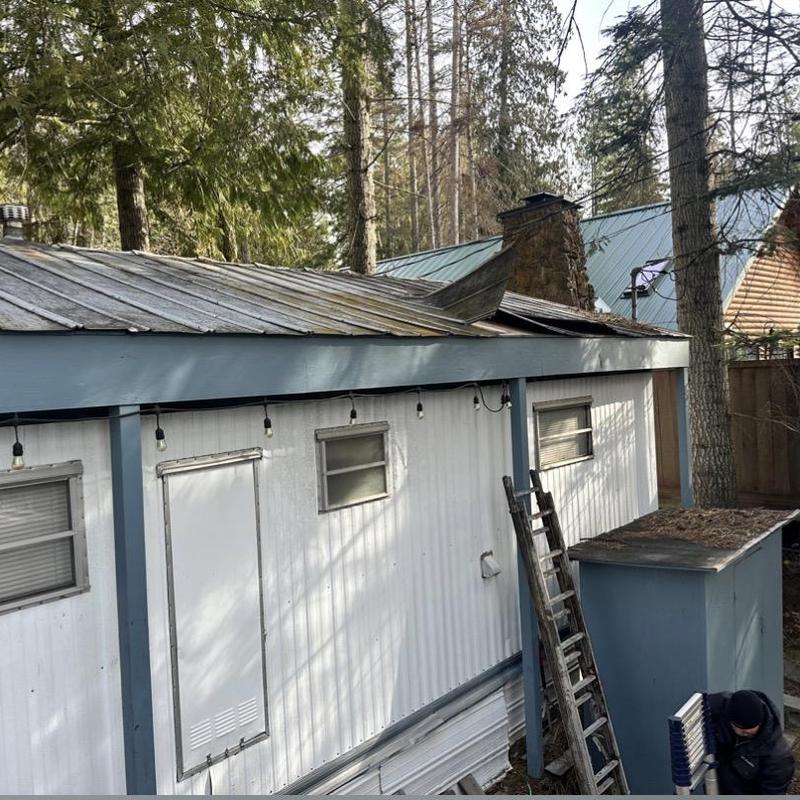 Metal roof with wind damage and inspection ladder