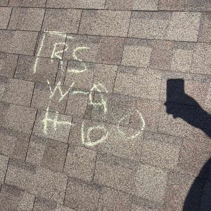 Roof shingles with chalk markings and inspector shadow