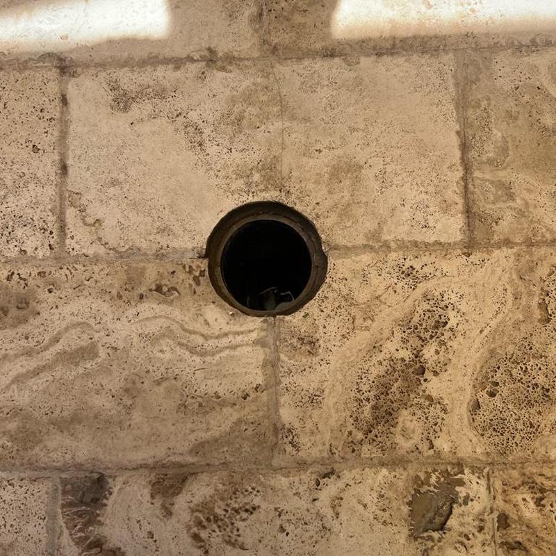 Area drain outlet cleared of rock blockage on tiled floor