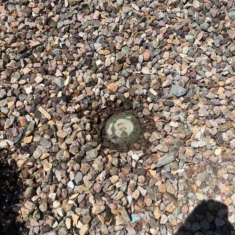 Area drain covered by gravel and stones outdoors
