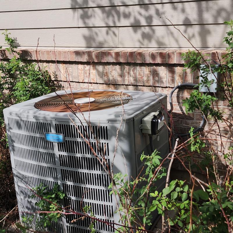 American Standard air conditioner outdoor unit near wall