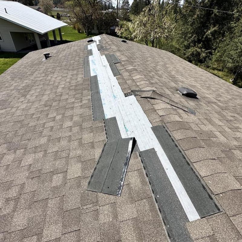 Roof shingles missing along ridge with exposed underlayment Roof shingles missing along ridge with exposed underlayment