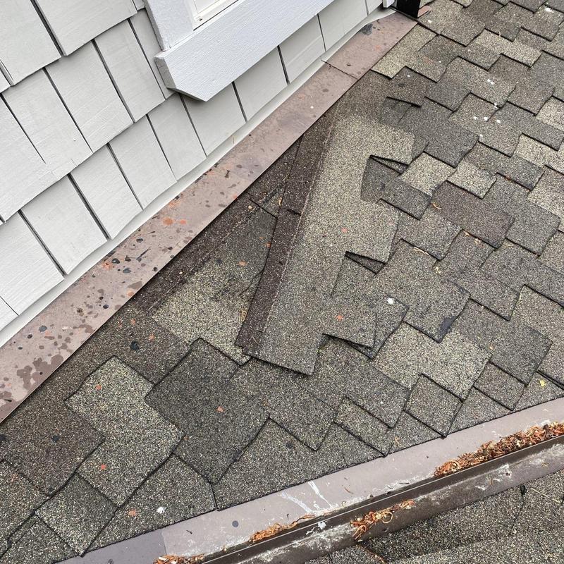 Roof shingles lifting near metal flashing on roof edge