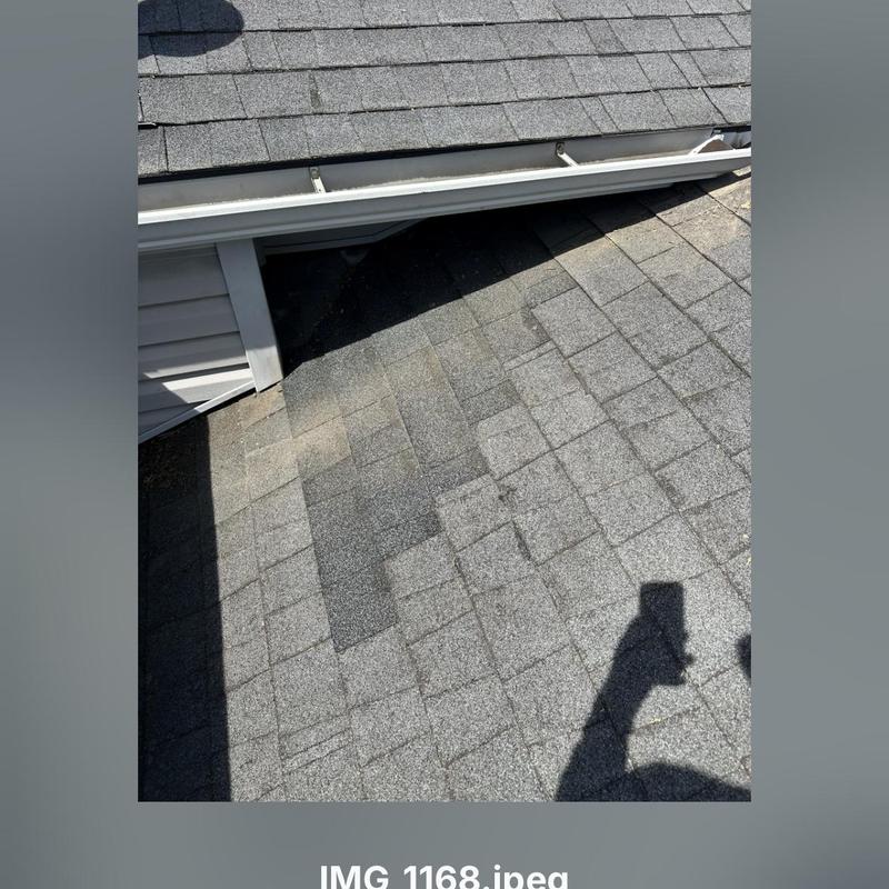Asphalt roof shingles with replaced patch near gutter
