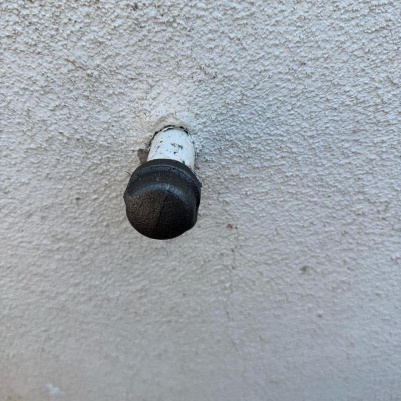 Black iron gas line cap on exterior wall