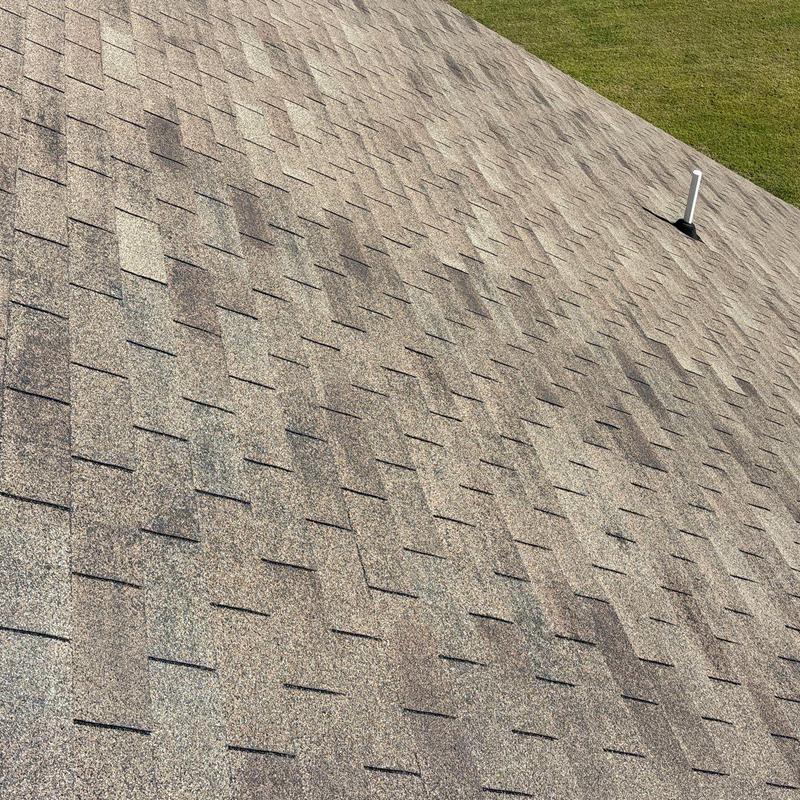 Roof shingles with hail damage and ventilation pipe