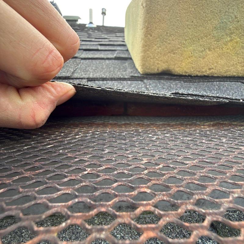 Roof shingle lifted to inspect hail damage and flashing