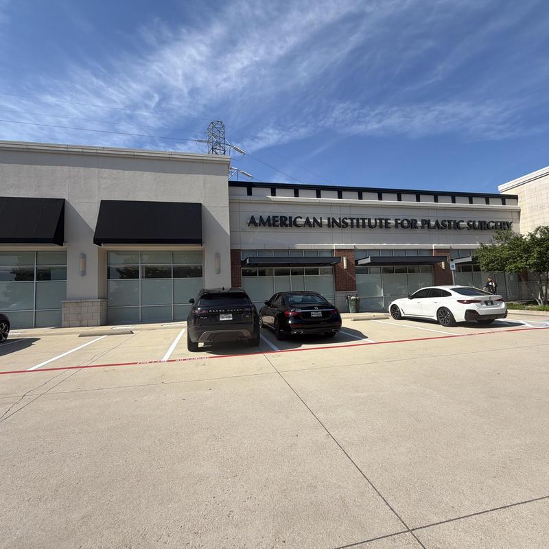 Stucco exterior wall with black awnings and signage