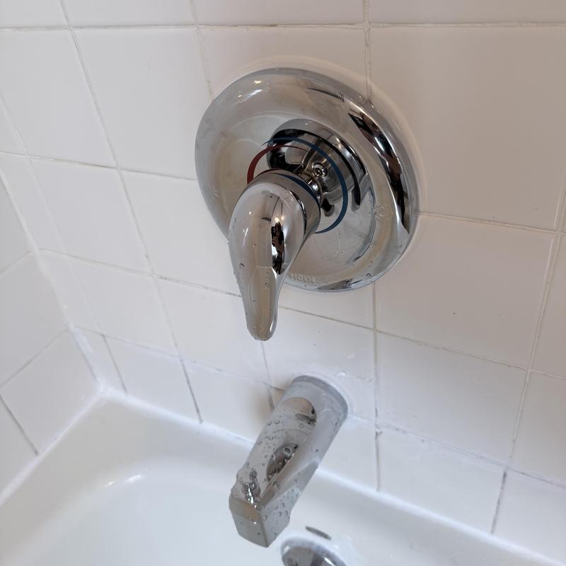 Shower valve handle and tub spout in white tile surround Shower valve handle and tub spout in white tile surround