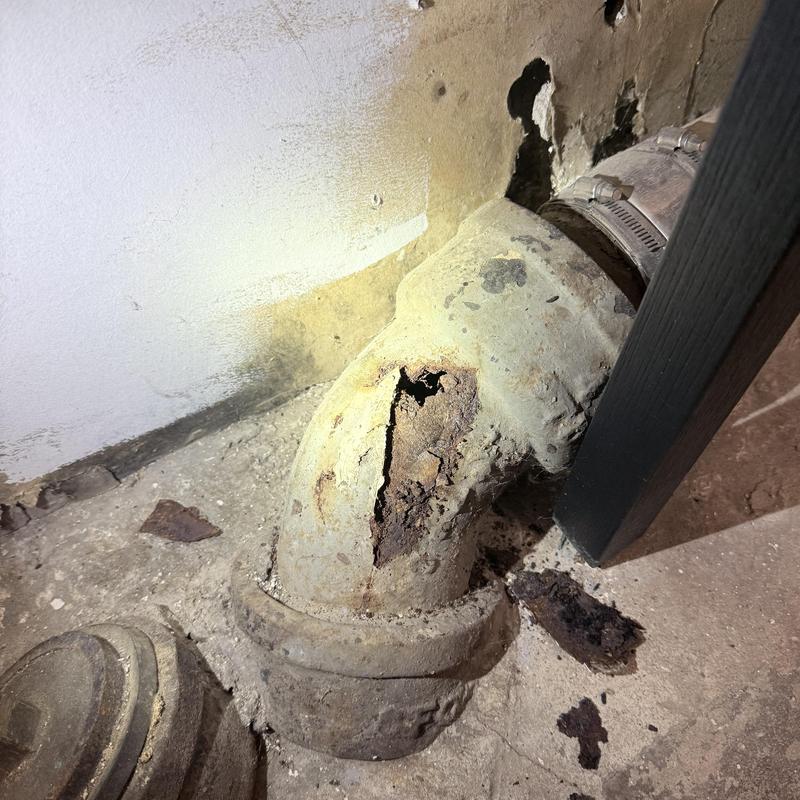 Cast iron pipe with large rust hole in basement wall Cast iron pipe with large rust hole in basement wall
