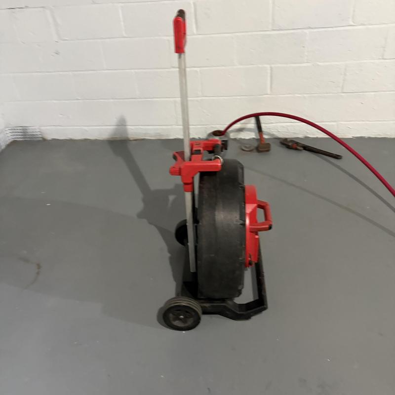 Drain cleaning jet machine with hose and tools on floor Drain cleaning jet machine with hose and tools on floor