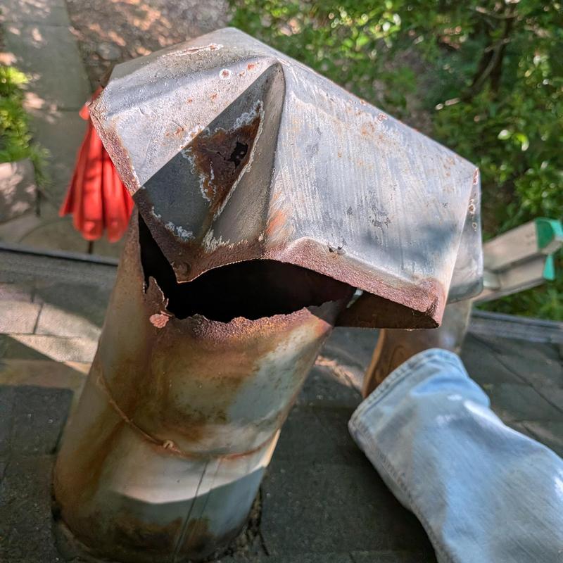 Metal chimney cap with rust and squirrel damage
