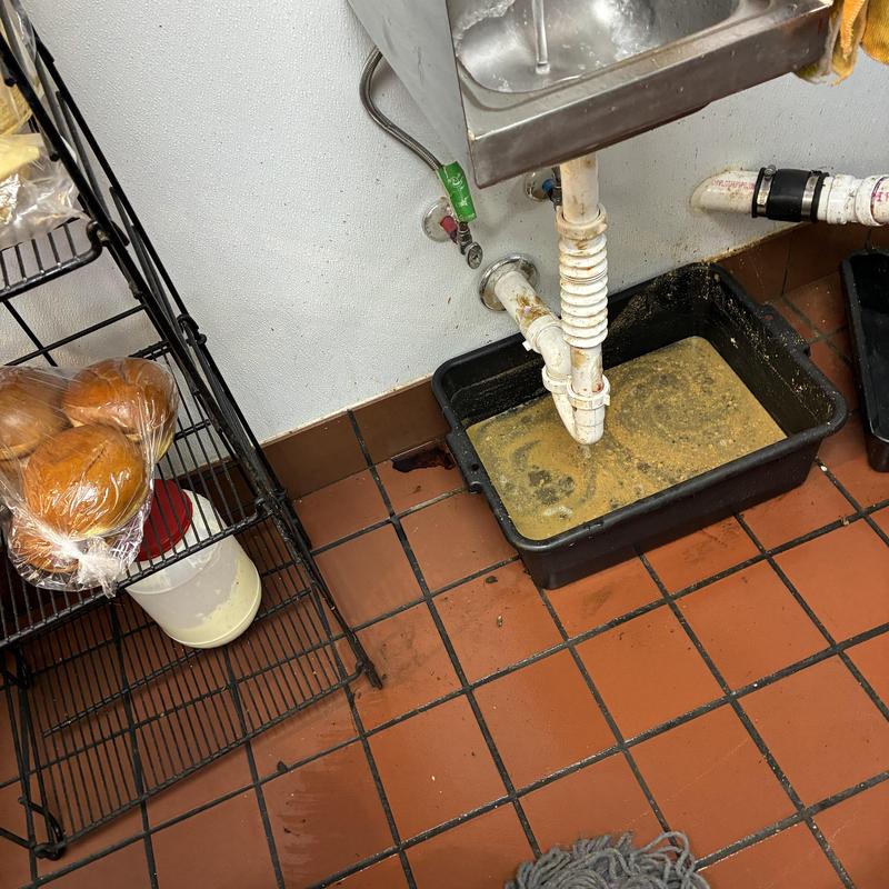 Hand sink P-trap with drain cleaning bucket in kitchen