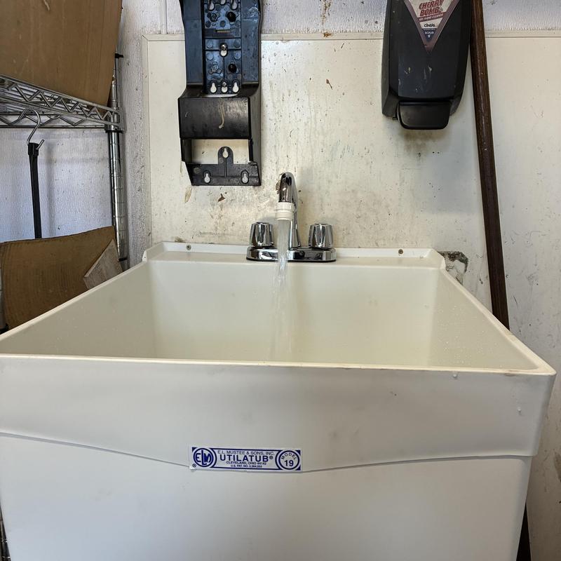 Industrial mop sink with running faucet in workshop Industrial mop sink with running faucet in workshop