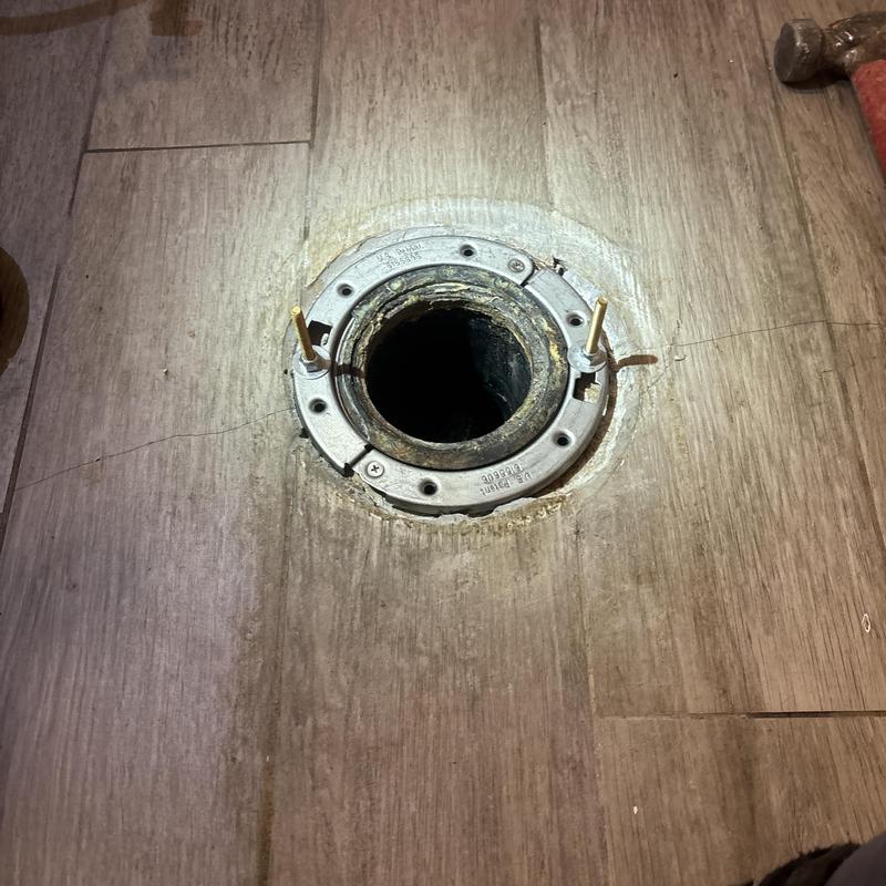 Toilet flange on wood floor with hammer nearby Toilet flange on wood floor with hammer nearby