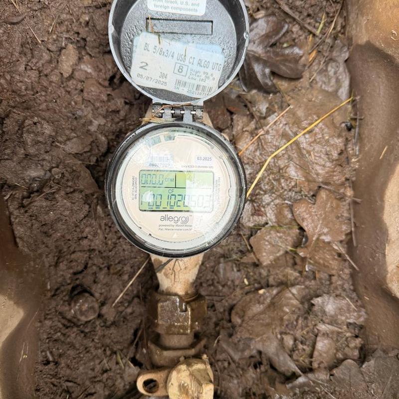 Water meter in dirt box with open lid and connections