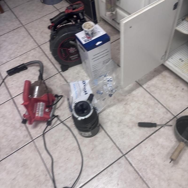 Garbage disposal unit and plumbing tools on tile floor Garbage disposal unit and plumbing tools on tile floor