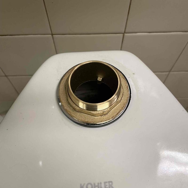 Flushometer valve brass fitting on toilet tank top