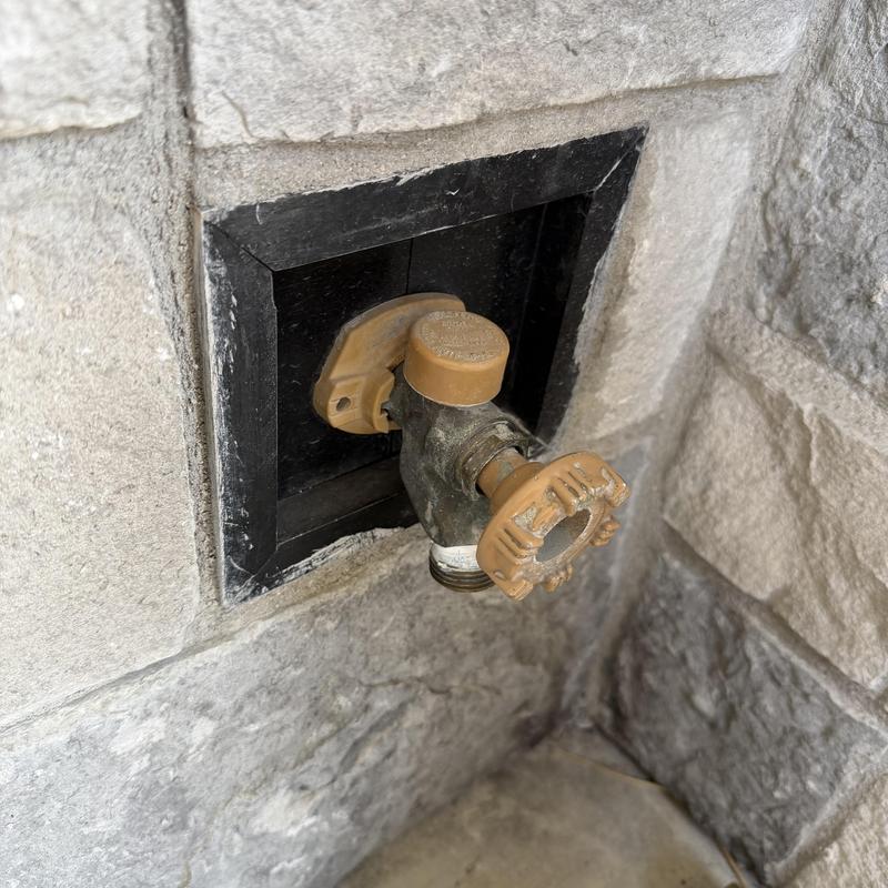 Hose bibb with vacuum breaker on stone wall Hose bibb with vacuum breaker on stone wall