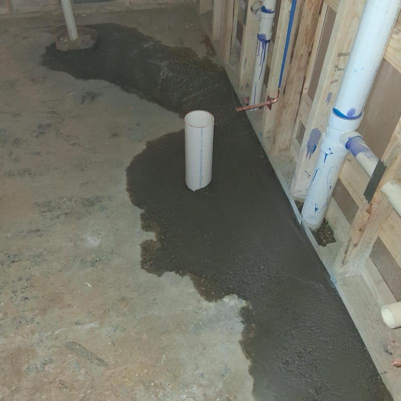Concrete patch around plumbing drain pipe in basement floor