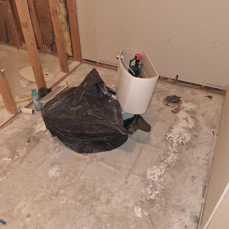 Toilet tank installation with plumbing and concrete patching