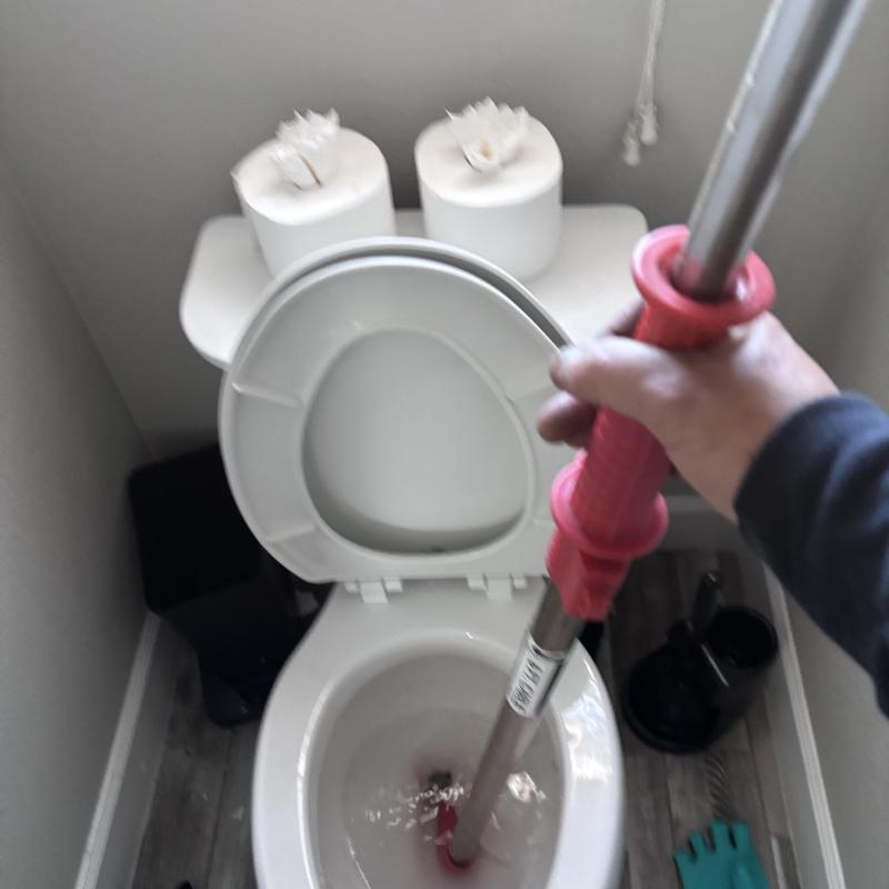 Toilet drain auger clearing clog in bathroom Toilet drain auger clearing clog in bathroom
