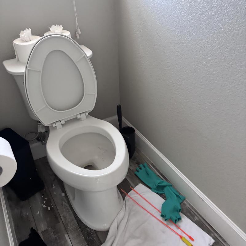 Toilet with auger tools and gloves on floor Toilet with auger tools and gloves on floor