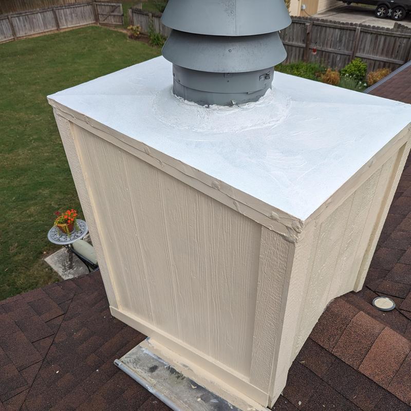 Chimney top with new white sealing on roof shingles