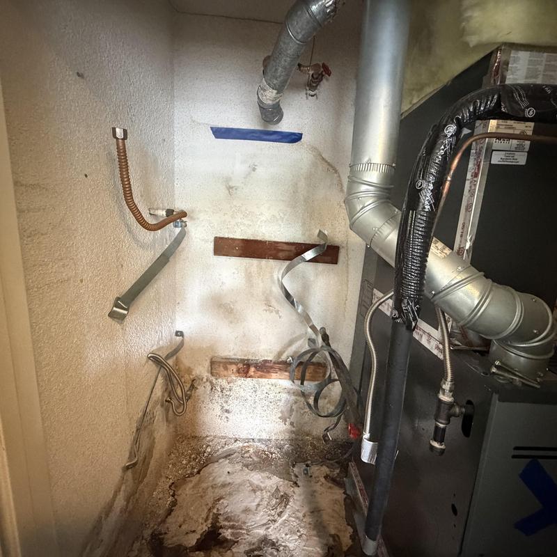 Water heater removal area with disconnected pipes and brackets