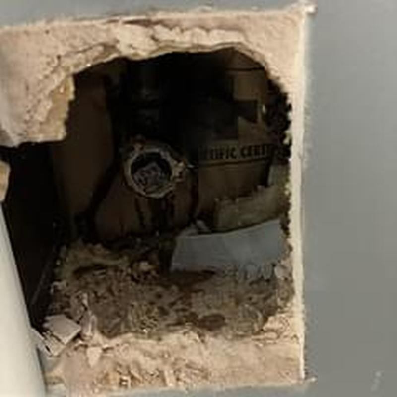 Gas pipe behind wall with capped fitting and debris