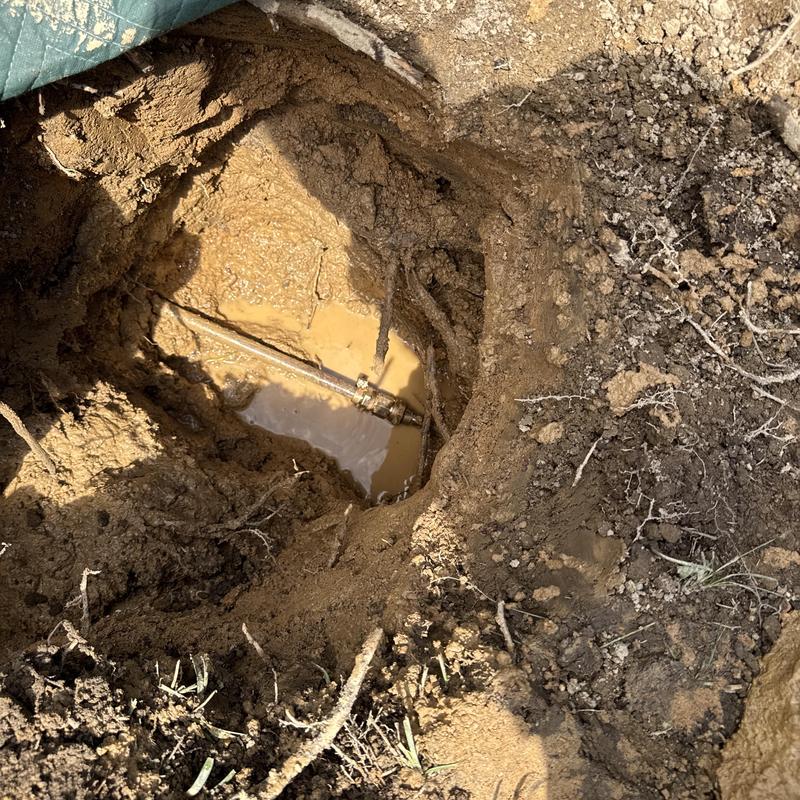 Copper main waterline exposed in muddy excavation hole Copper main waterline exposed in muddy excavation hole