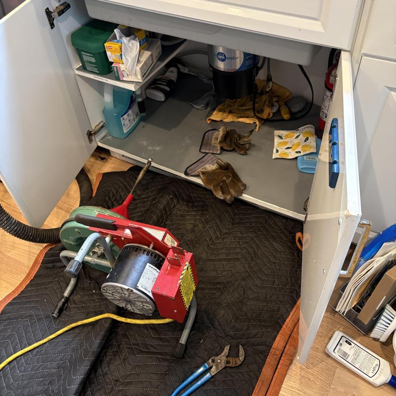 Kitchen drain line cleaning machine near cabinet open doors Kitchen drain line cleaning machine near cabinet open doors