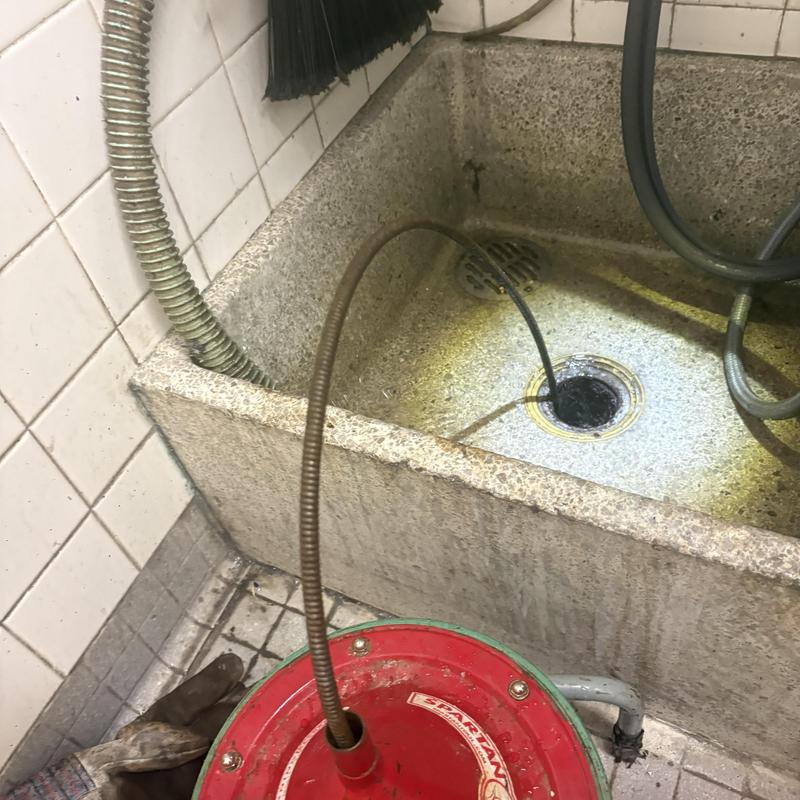 Drain cleaning snake in utility sink with cleaning gloves nearby Drain cleaning snake in utility sink with cleaning gloves nearby