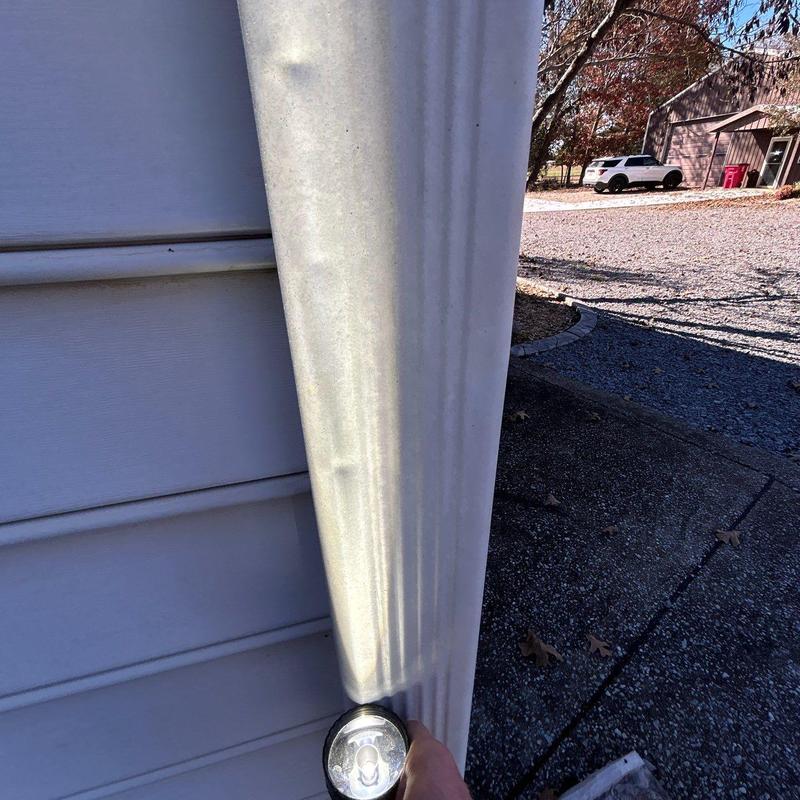 Vinyl siding panel inspection with flashlight in sunlight