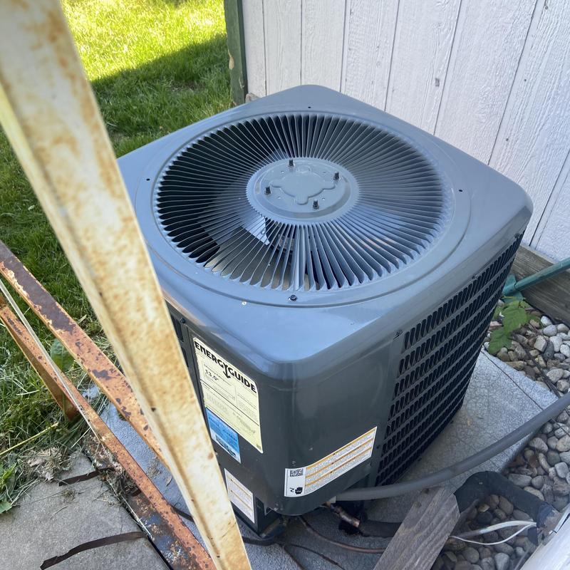 HVAC condenser unit outdoors with security bars nearby