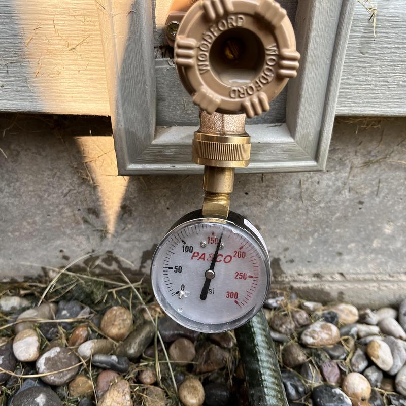 Hose bib pressure gauge reading 85 psi near home wall