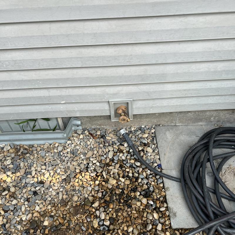 Hose bibs with garden hose connected to home wall