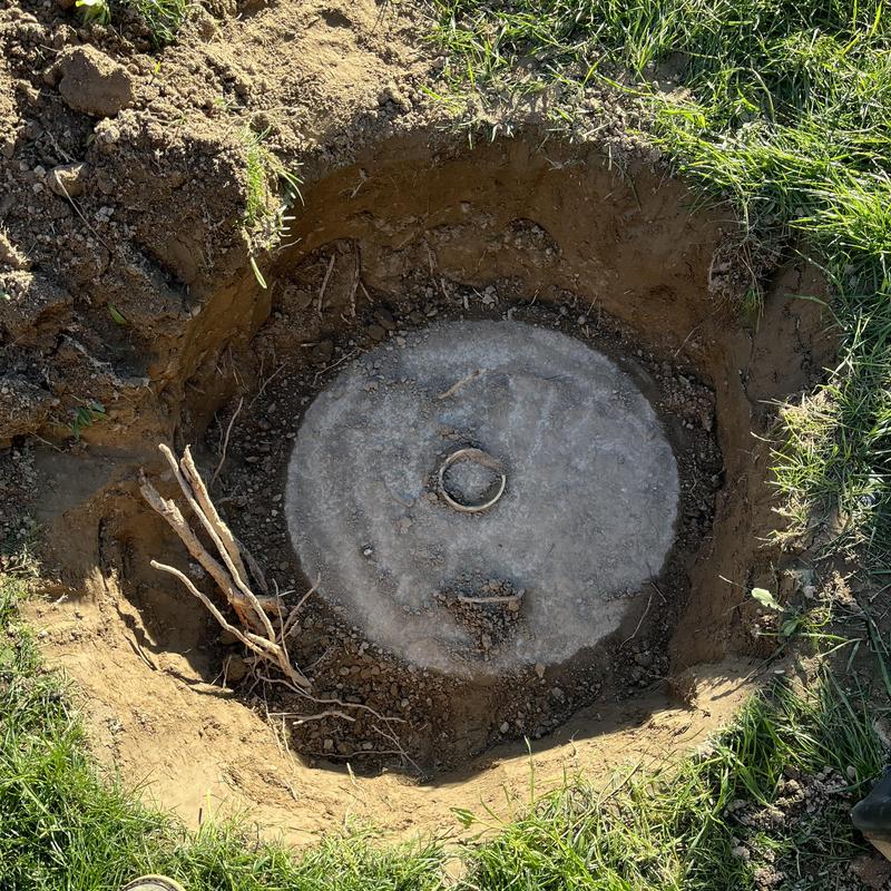 Septic tank lid exposed in dug-out soil hole