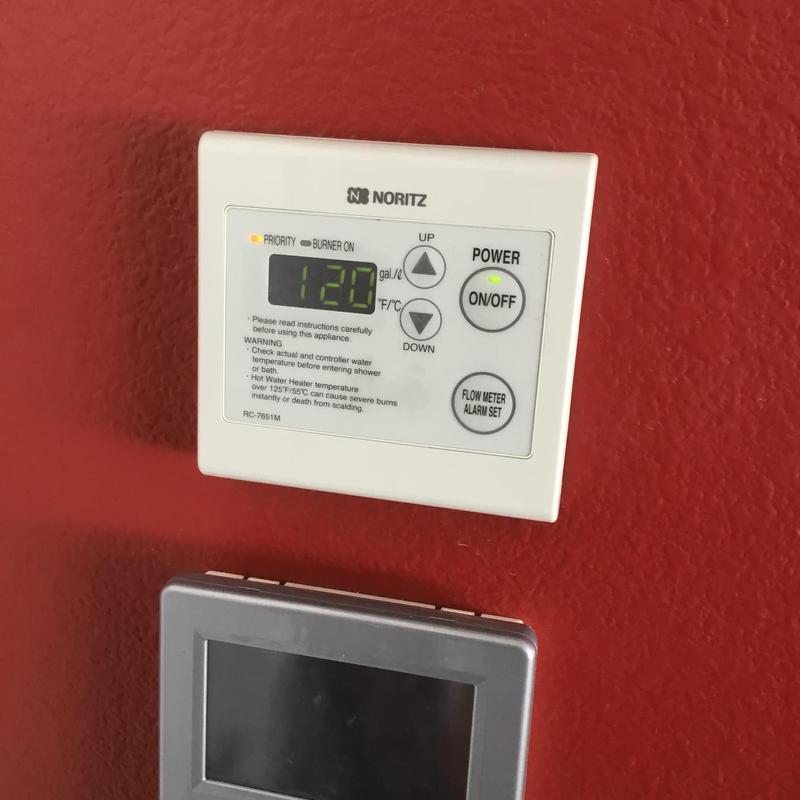 Tankless water heater digital control panel on red wall Tankless water heater digital control panel on red wall