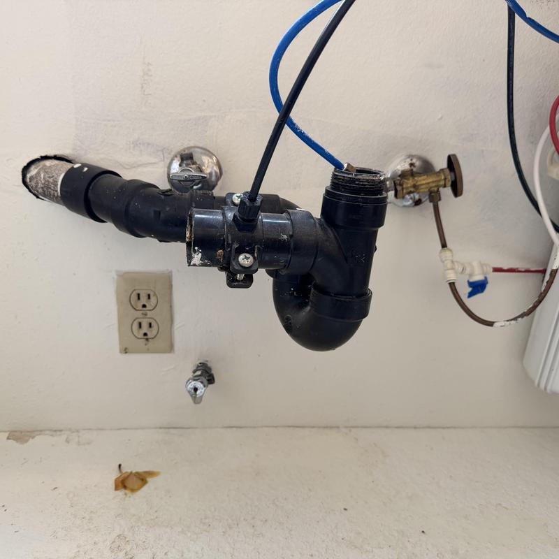 Black PVC sink drain piping under sink with valves