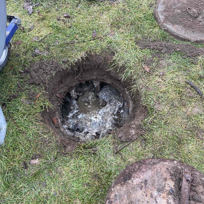 Septic tank opening dug up showing solids buildup