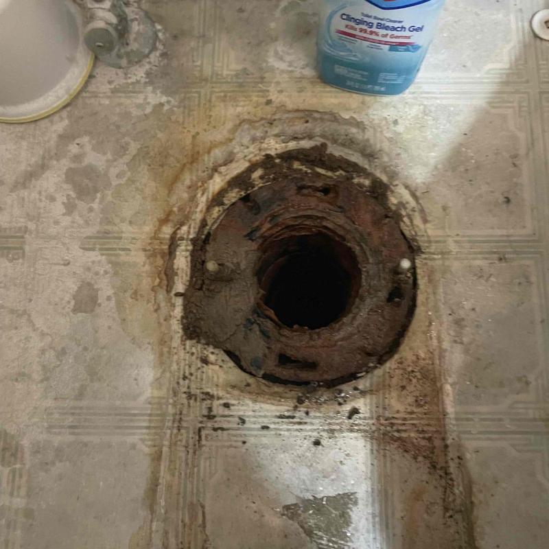 Toilet flange with corrosion on bathroom floor
